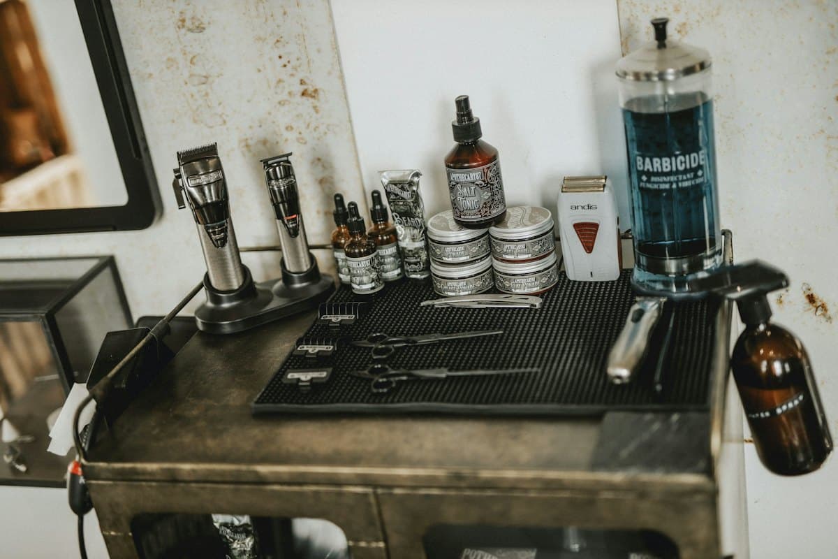 A steel barber station with tins of pomade, bottles of oil and tonic, clippers and a jar of disinfectant