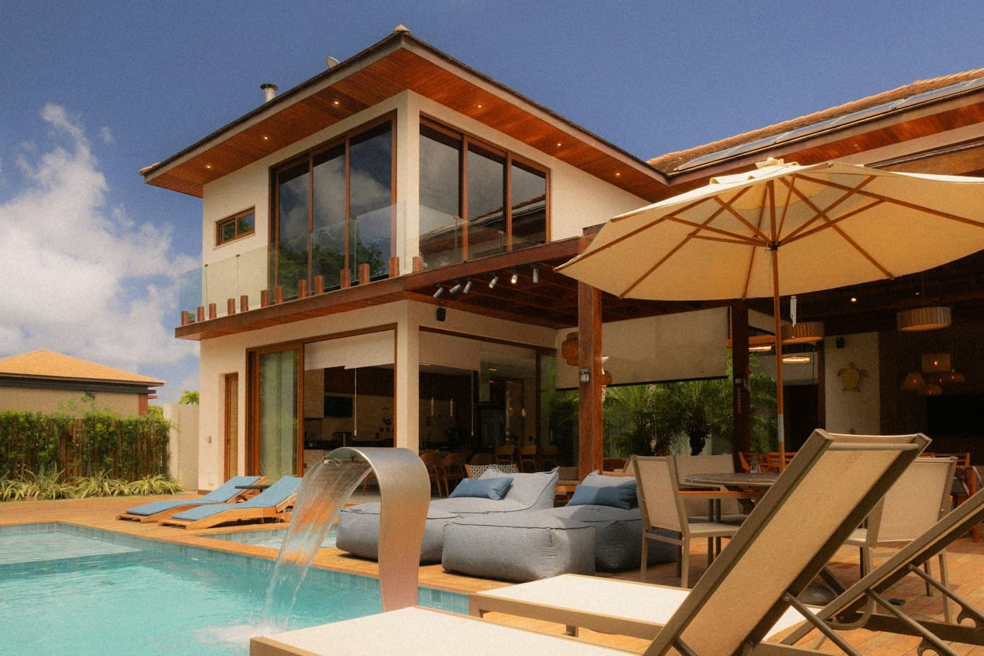 Renovated two-storey villa with timber eaves behind a pool terrace
