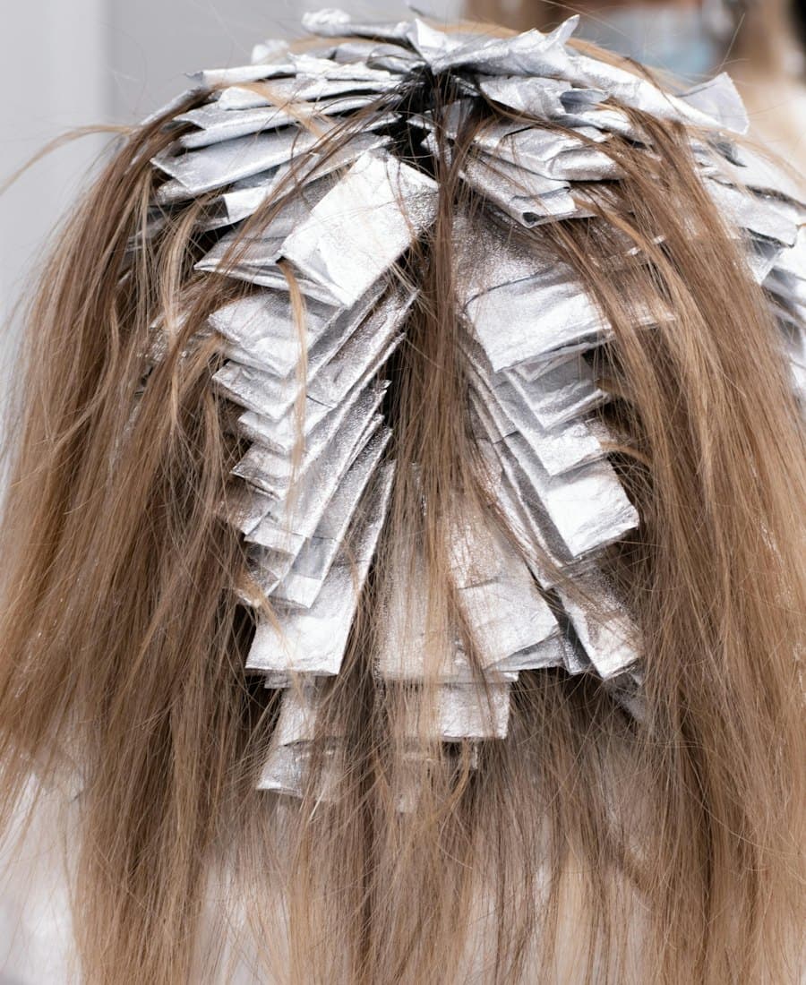 The back of a head of light brown hair sectioned into rows of folded silver foils during a highlighting service