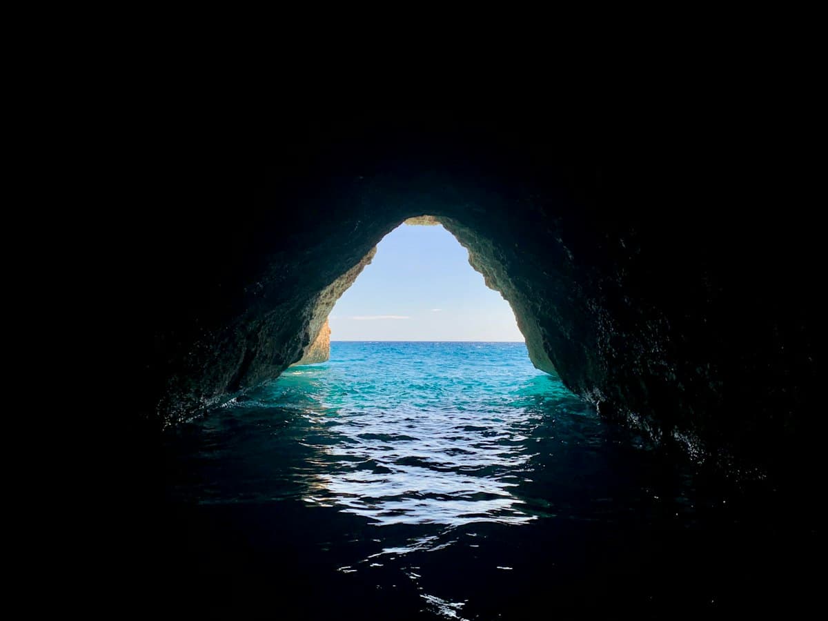 Looking out from inside a dark sea cave onto bright turquoise water