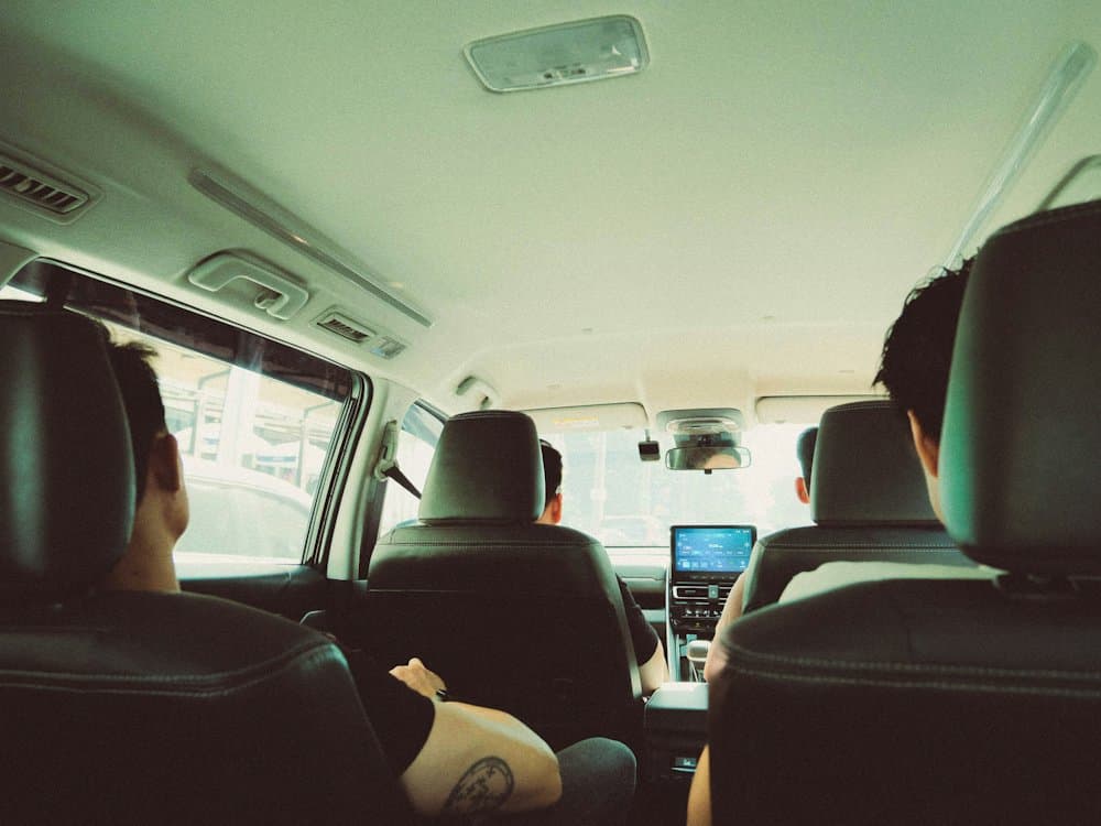 Passengers seen from the back row of a van, with the road ahead through the windscreen